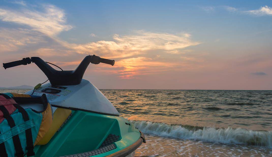 Moto de agua en la playa con el atardecer de fondo